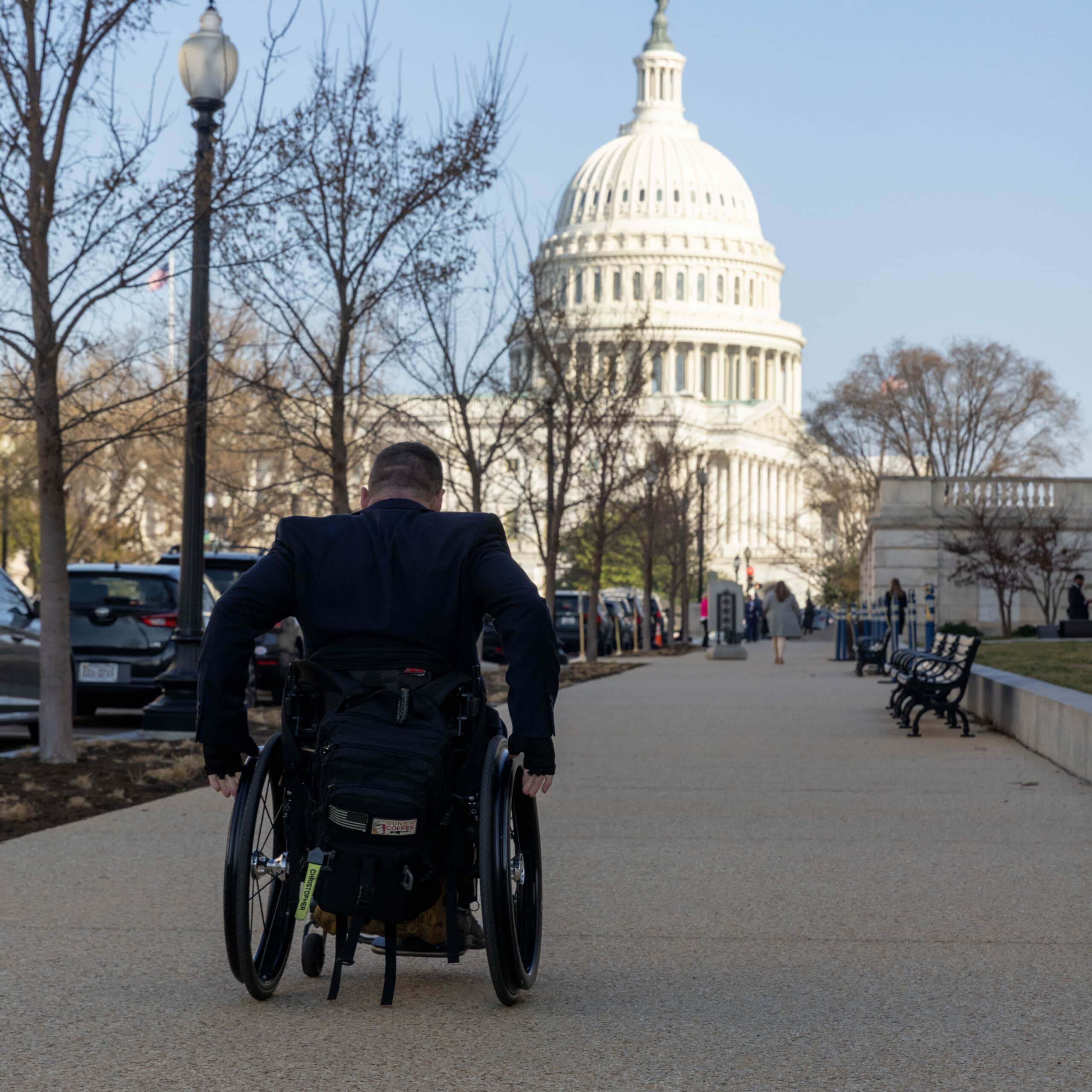 man in suit in wheelchair in front of capital building